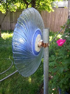 a large blue object sitting on top of a metal pole next to a flower garden