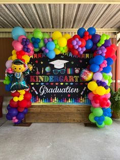 an arch made out of balloons with a graduation sign in the middle and some other decorations around it