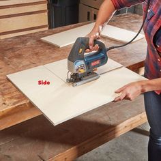 a woman using a sanding machine to cut out plywood planks on a table