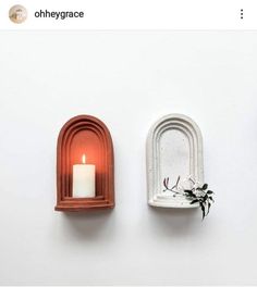 there are two wall shelves that have candles on the top and one with a candle in it