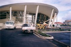 two trucks are parked in front of a large building with columns on the side and scaffolding around it