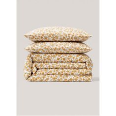 three pillows stacked on top of each other in front of a gray background with white and yellow flowers