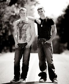 two young men standing next to each other on top of a skateboard in the street