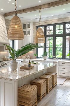 a large kitchen with white cabinets and marble counter tops, two hanging lights above the island