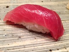 a piece of sushi sitting on top of a wooden table