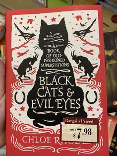 a book with black cats and evil eyes written on it in front of bookshelves