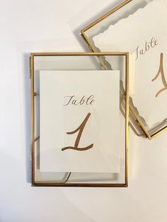 the table numbers are in gold frames with white paper and brown writing on them,