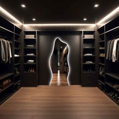 a walk in closet with black walls and wooden flooring, lighted by recess lighting