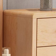 a wooden dresser with two drawers and a bottle of lotion next to it on the floor