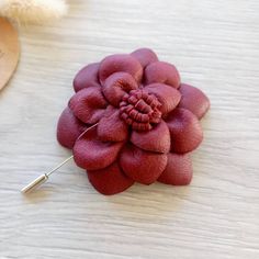 a red flower brooch sitting on top of a wooden table