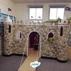 an indoor play area for children with a castle made out of rocks and paper machs