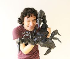 a young man holding up a sculpture of a scorpion