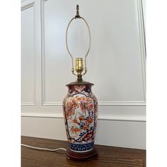 a lamp that is sitting on top of a wooden table next to a wall with white paneling