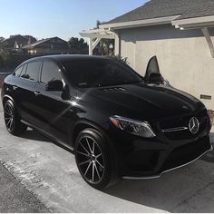 a black mercedes suv parked in front of a house