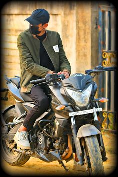 a man sitting on top of a motorcycle in front of a wooden building and wearing a hat