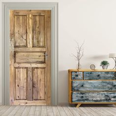 an empty room with a wooden door and dresser in front of it, next to a white wall