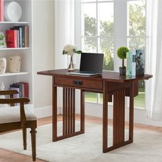 a laptop computer sitting on top of a wooden desk in front of a book shelf