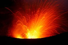 an orange and red firework is lit up in the night sky with dark background