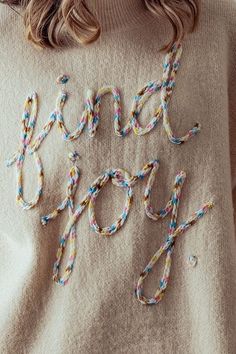 a woman wearing a sweater with the words hand soap written on it in multicolored braids