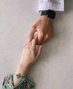 two people touching each other's hands on a white surface with one holding the other hand