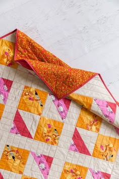 an orange and pink quilted blanket laying on top of a table