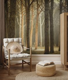 a room with a chair, book and large wall mural in the background that has a forest scene on it