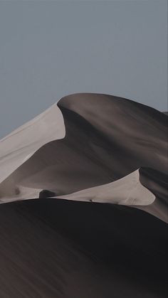 a person riding a snowboard on top of a large sand dune in the desert