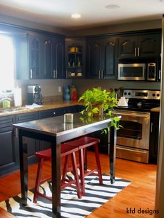 a kitchen with black cabinets and stainless steel appliances is pictured in this image, the island has two stools on it