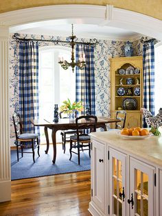 an archway leads into a dining room with blue and white wallpaper on the walls