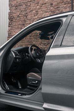 the interior of a silver car with its door open and it's driver inside