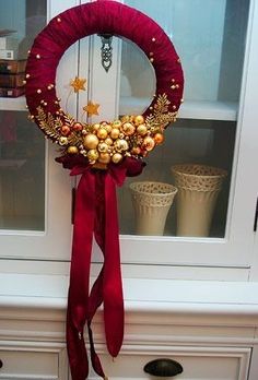 a christmas wreath is hanging on the front door with red ribbon and gold ornaments around it