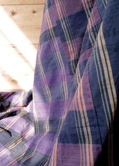 a purple and blue plaid comforter sitting on top of a bed next to a wooden wall