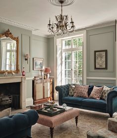 a living room filled with furniture and a chandelier hanging from the ceiling over a fire place