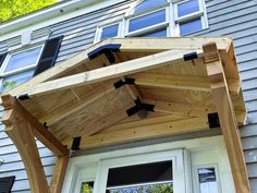 a wooden roof over a white door in front of a house