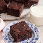 two plates with brownies on them next to a glass of milk