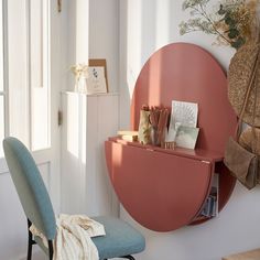 there is a pink shelf on the wall next to a blue chair and other items