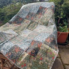 a quilted blanket sitting on top of a wooden table next to potted plants