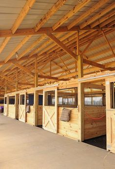 the inside of a barn with wooden stalls and windows on each side, lined up against the wall