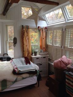 a bed room with a neatly made bed next to two windows covered in curtains and blankets