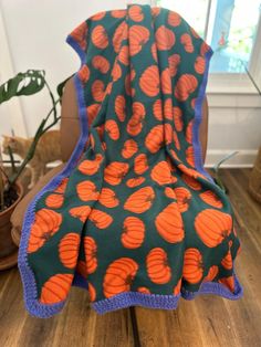 an orange and blue blanket sitting on top of a wooden table next to a potted plant