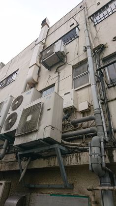 an air conditioner on the side of a building with pipes running from it's sides