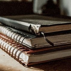 three books are stacked on top of each other, one is open and the other has an empty bookmark