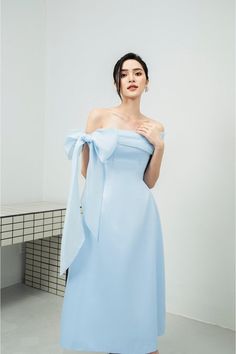 Possesses a basic dress form that helps to flatter the curves of the body A very simple but extremely poetic design with a drop shoulder design, knotted to create a lovely bowtie. Pastel blue tones express pure, gentle beauty, bringing a sense of peace. Product Details - Product type: Midi Dress- Material: Organza, Taffeta- Draped off-shoulder - Big bowtie at the shoulder - Fitted waist - A-line skirt - Length: 115cm Size & Fit - Model wears size: S- Model measurement: 170cm, 86-62-88 Care Instr Bowtie Dress, Hijab Prom Dress, Chinese Fancy Dress, Bow Tie Dress, Mean Blvd, Elegant Dresses Classy, Basic Dress, Fashion Mistakes, Dress Form