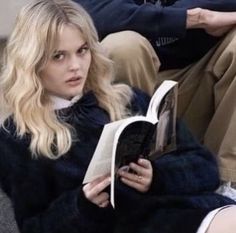 a woman sitting on a couch reading a book