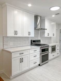 an empty kitchen with white cabinets and stainless steel stove top oven in the center area