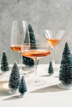 three wine glasses filled with champagne and small christmas trees