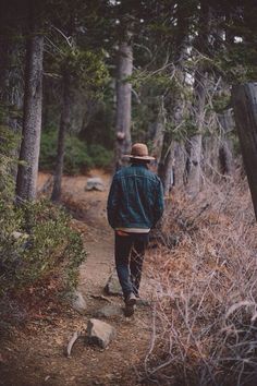 a man walking down a trail in the woods