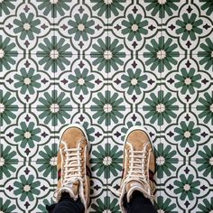 someone's shoes are standing on the floor in front of a green and white tile pattern