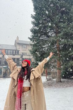 a woman standing in the snow with her arms outstretched