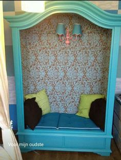 a room with a blue bed and two lamps on the headboard, in front of a wallpapered background